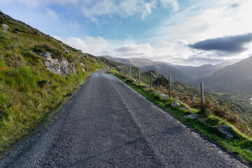 Fototapeta na wymiar narrow road with asphalt and green grass through hills and valley on the wild Atlantic way in ireland with no cars on it