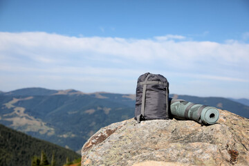 Sleeping bag and camping mat on mountain peak, space for text