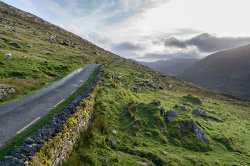 narrow road with asphalt and green grass through hills and valley on the wild Atlantic way in...