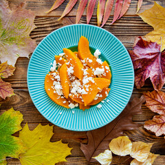 Autumn salad with pumpkin and feta cheese, top view. Vegan and meatless. Colorful leaves background. 