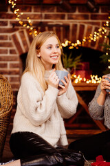 a beautiful blonde drinking cocoa by the New Year's fireplace
