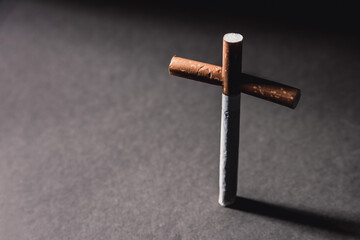 Cross from a cigarette lies against a dark background.