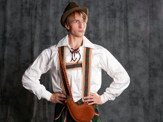 Fototapeta na wymiar A young man in a national Bavarian suit with shorts on suspenders and a hat.
