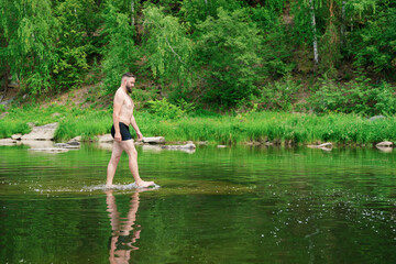 A man walks barefoot on the surface of the water like jesus. The tourist is preparing to sail. The young man enjoys water treatments. The traveler stopped by the river to swim. Copy space