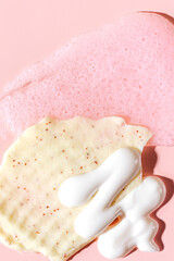 Various cosmetic mask, creams, serum, scrub and lotion smear on a pink background. Beauty texture. Sample of a cosmetic product.