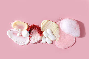Composition of various cosmetic mask, creams, serum, scrub and lotion smear on a pink background. Beauty texture. Sample of a cosmetic product.
