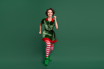 Photo of cute adorable young woman dressed elf costume jumping high running fast smiling isolated...
