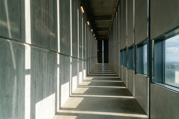 Long concrete corridor with vertical windows in a building