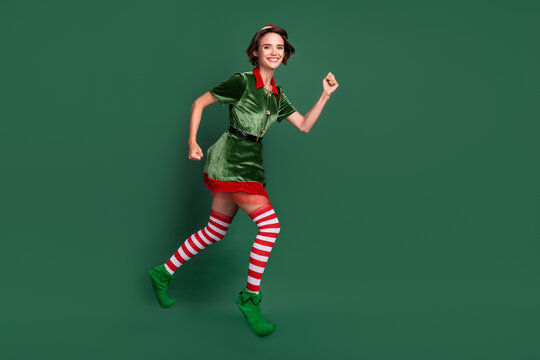 Photo of charming cute young woman dressed elf costume jumping high running fast smiling isolated green color background