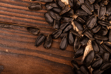 Fried black sunflower seeds scattered on the table, close-up, selective focus.