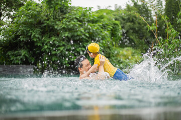 Father and son fun in water pool at summer day.