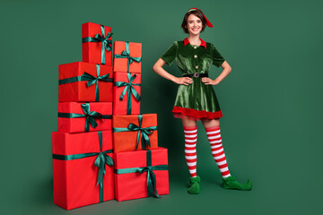 Photo of cheerful delivery helper lady pile presents wear elf costume hat stockings isolated green...