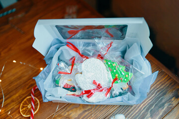 Christmas children's gift with gingerbread in icing. Box of cookies, decorations and garland on wooden table. Festive composition.