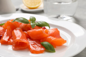Salmon carpaccio with basil on plate, closeup