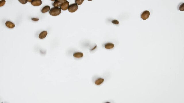 The coffee beans spin rotate quickly fast fly, dispart, splash to the sides with centrifugal coriolis force. The video is in reverse. Twist, create pattern, make design picture. Pressurized air wind.