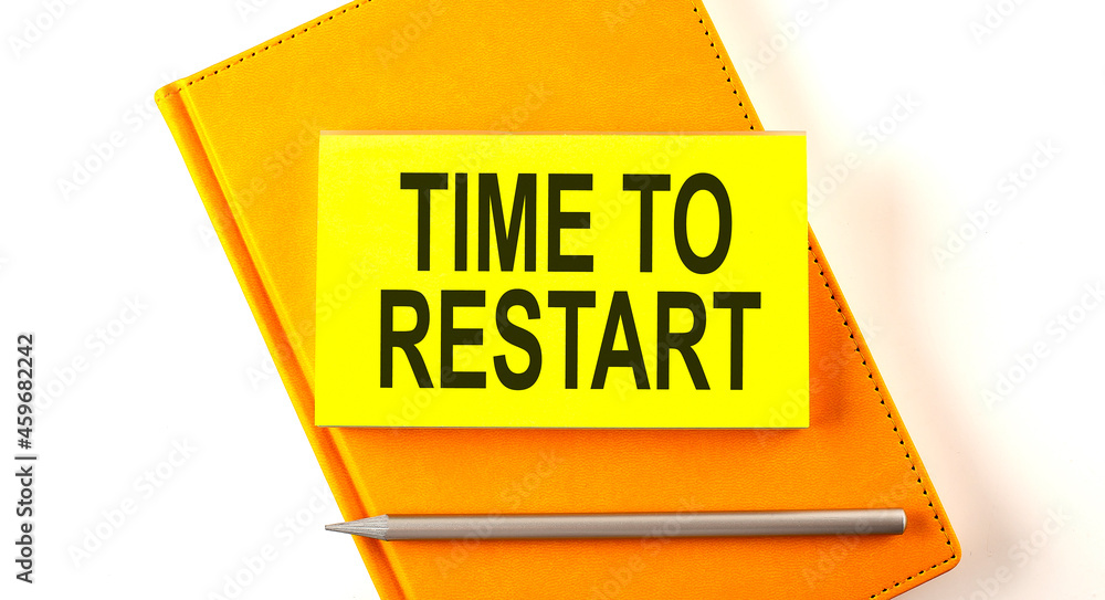 Poster text time to restart on the sticker on the yellow notebook