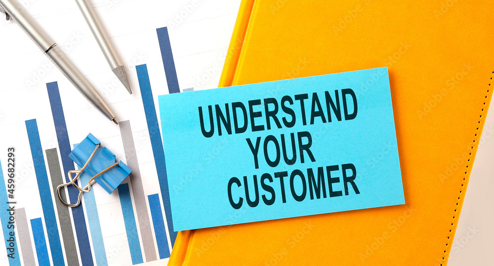 Poster understand your customer text on sticker on the yellow notebook with chart and pen