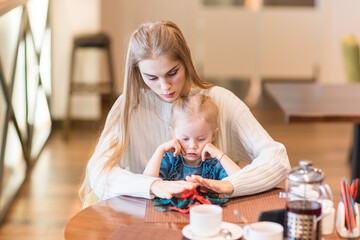 The girl shows her tongue. Mom with a naughty child