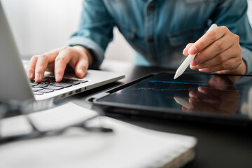close up of investor women using tablet and laptop computer trading stock market via apps online at...