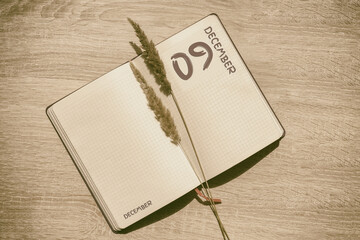 december 9. 9th day of month, calendar date.Blank pages of notebook are beige, with dried...