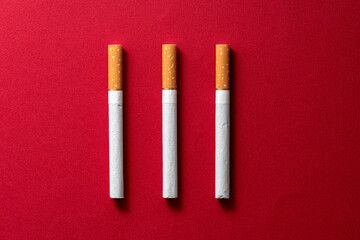 Three pieces cigarette evenly spaced on a dark red