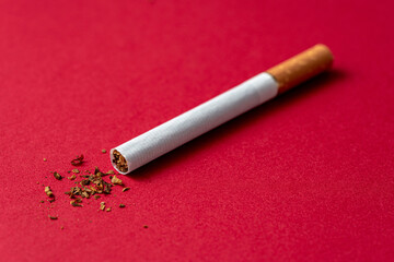 One cigarette evenly located on a red background.