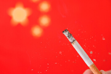 Hand and cigarette on the background of the flag of china.
