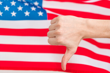 Hand in the background of the flag USA shows a bad gesture.