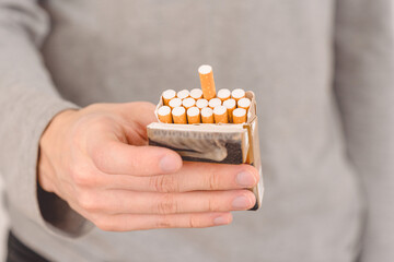 A man offers a cigarette. One cigarette is plucked from