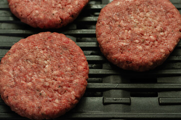 Seasoned beef burgers with a pinch of salt and black pepper on the grill