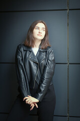 Portrait of a young woman in an autumn black leather jacket. Modern urban style clothing black...