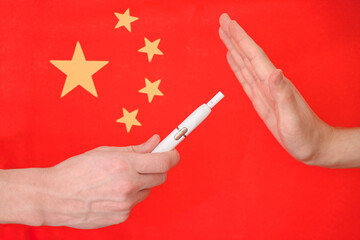Hand and cigarette on the background of the flag of china.