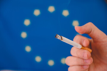 Hand holds a steaming cigarette on the background