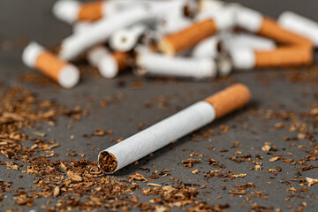 Cigarette and a bunch of cigarette butts in the background.