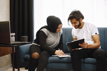 Young students, arab couple preparing for exams in apartment interior