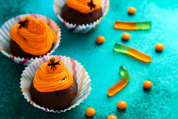 Holidays, decorations and party concept - Halloween cupcakes and candies on green background
