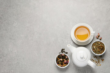 Fresh brewed tea and dry leaves on light grey background, flat lay. Space for text