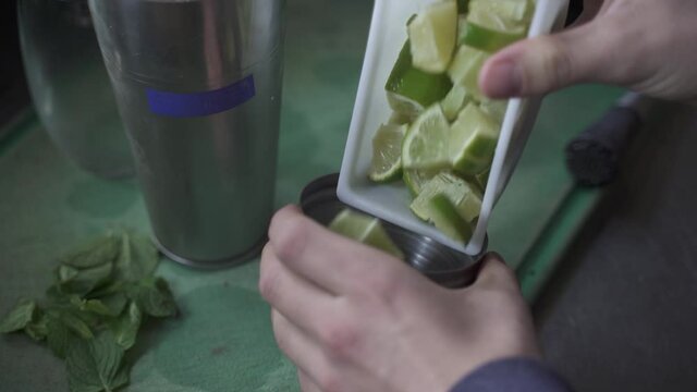 Unrecognizable bartender adding lime slices in cynar drink. Slow-motion and close up