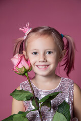 Little caucasian girl in a festive dress with sequins posing with rose flower