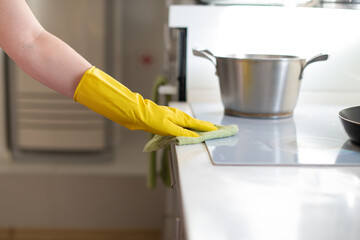 Professional cleaning of apartments and houses. General cleaning in the kitchen. Wipe the plate and surfaces. Washing the faucet and sink. Cleaning lady in uniform, apron, rubber gloves