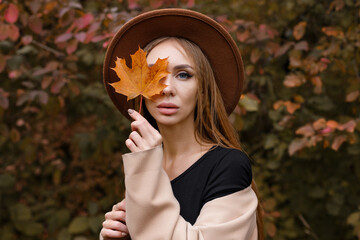 portrait of a woman with autumn makeup and autumn leaf. close-up