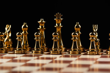 Golden chess figures standing on chessboard