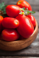 Fresh tomatoes in a bowl on a wooden background