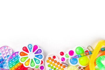 Modern trendy kids fidget finger toys, relaxation concept - set of different bright pop-it, simple-dimple, squishy, pop-tubes, on white background, top view copy space