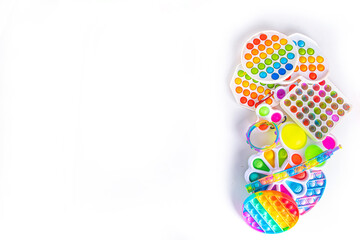 Obraz premium Modern trendy kids fidget finger toys, relaxation concept - set of different bright pop-it, simple-dimple, squishy, pop-tubes, on white background, top view copy space