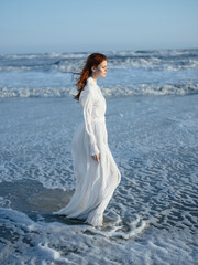 Fototapeta na wymiar Woman in white dress outdoors beach ocean walk