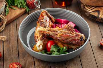 Gourmet prepared lamb legs dish with vegetables on wooden background