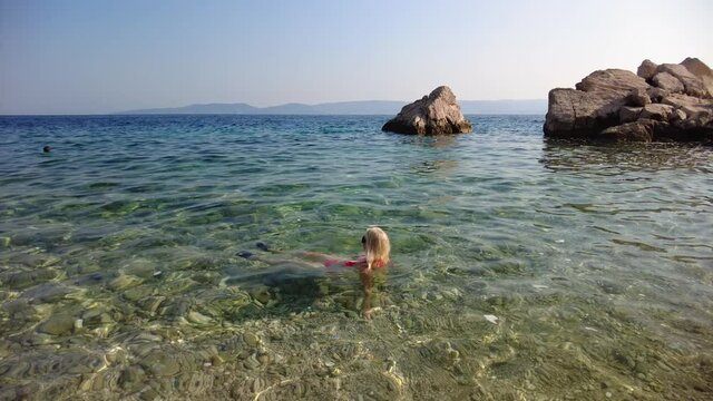 Woman in bikini in the sea of Borka beach in Marusici village of Croatia. Swimming in Croatian Adriatic Sea of Dalmatia in the Split city area close to Makarska.