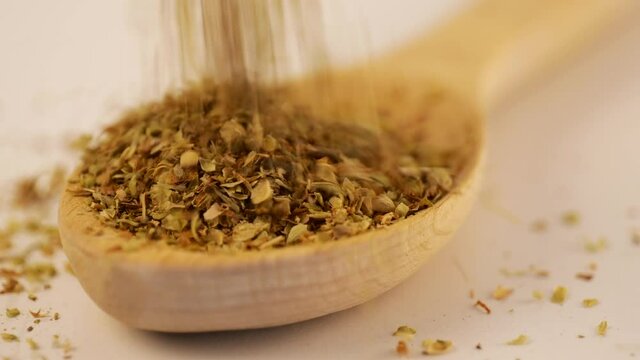 Dry oregano strewed from above into a wooden scoop