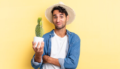 hispanic handsome man shrugging, feeling confused and uncertain farmer and cactus concept